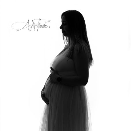 Silhouette d'une femme enceinte, en robe légère, se tenant le ventre.